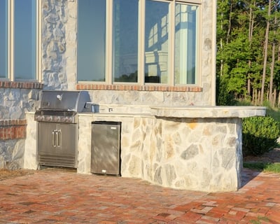 Slide-in grill encased in stone on brick patio
