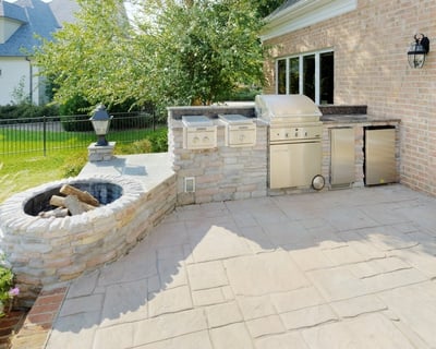 Stone kitchen and fire pit with slide-in grill, power burners, and accessories